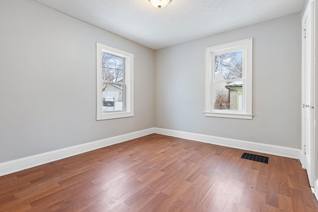 spare room with a textured ceiling and hardwood / wood-style flooring