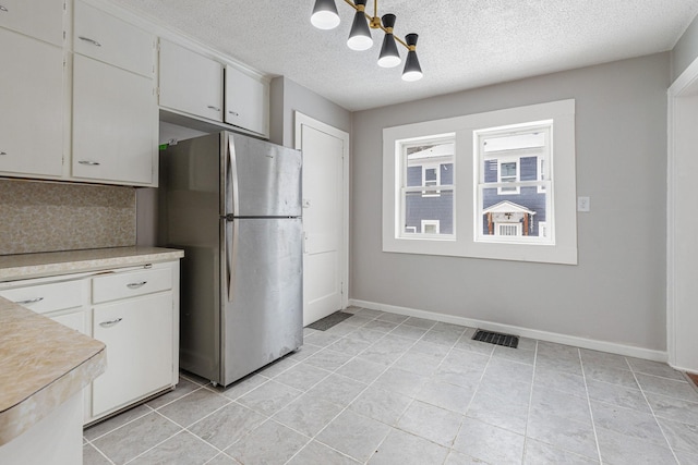 kitchen featuring a textured ceiling, white cabinetry, and stainless steel fridge