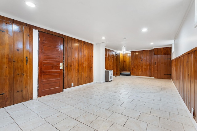 tiled empty room with crown molding and wood walls