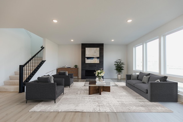 living room with a tiled fireplace and light hardwood / wood-style flooring