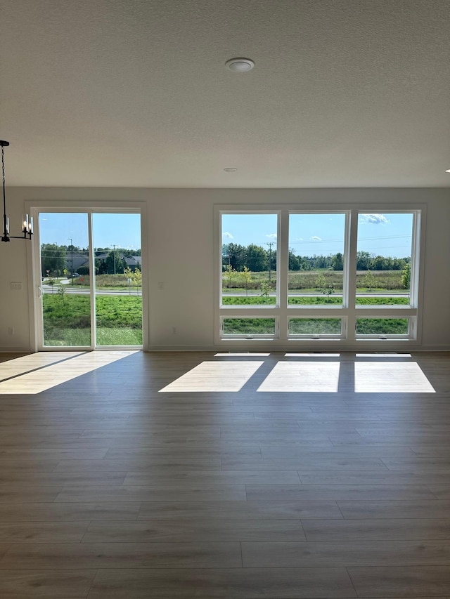 unfurnished room with dark hardwood / wood-style floors, a notable chandelier, and a healthy amount of sunlight