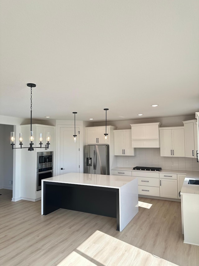 kitchen featuring appliances with stainless steel finishes, pendant lighting, white cabinetry, and a kitchen island