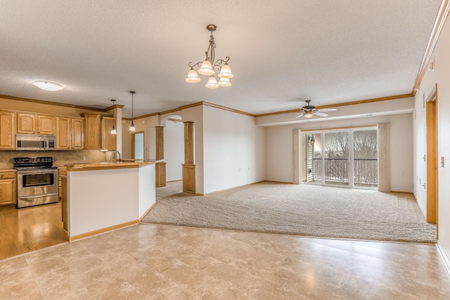 kitchen with stainless steel appliances, kitchen peninsula, crown molding, and decorative light fixtures