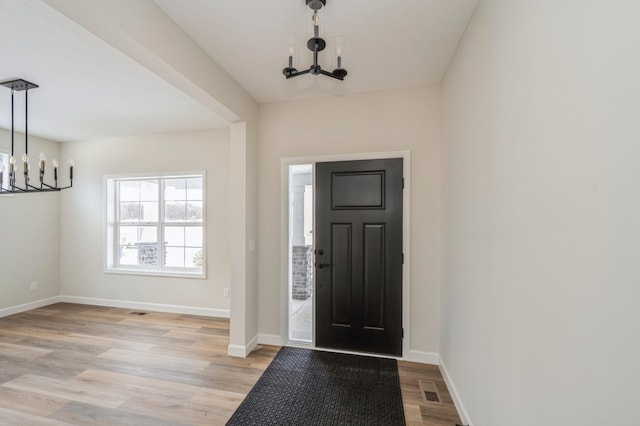 foyer featuring light wood-type flooring and a notable chandelier