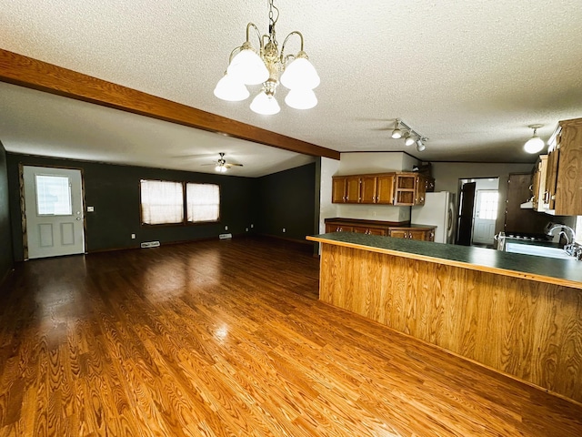 kitchen with hanging light fixtures, fridge, a textured ceiling, and kitchen peninsula