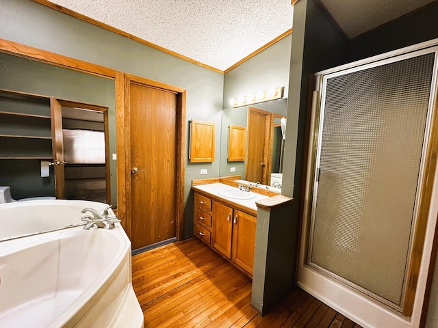 bathroom with shower with separate bathtub, wood-type flooring, lofted ceiling, vanity, and ornamental molding