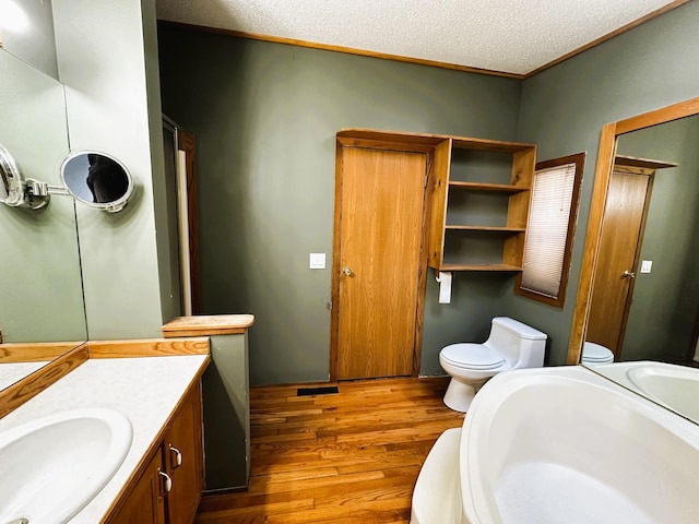 bathroom with vanity, hardwood / wood-style floors, a textured ceiling, and toilet