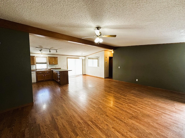 unfurnished living room with sink, hardwood / wood-style floors, track lighting, a textured ceiling, and ceiling fan with notable chandelier