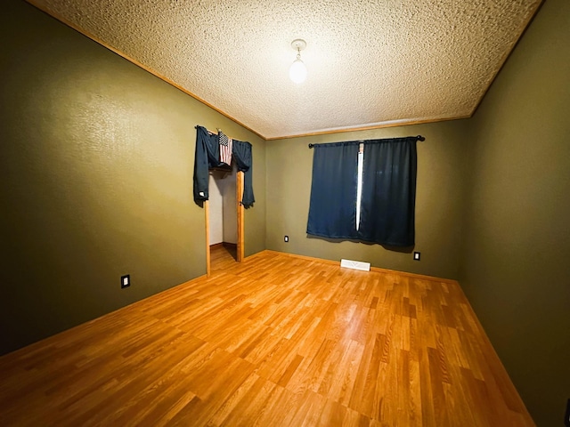 empty room with crown molding, wood-type flooring, and a textured ceiling