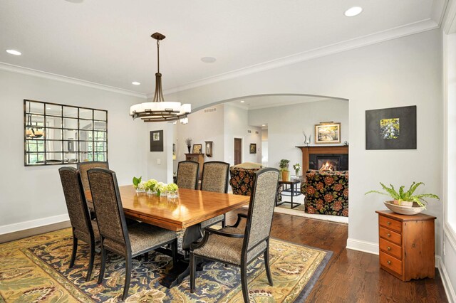 dining room with dark wood-type flooring, ornamental molding, and a notable chandelier