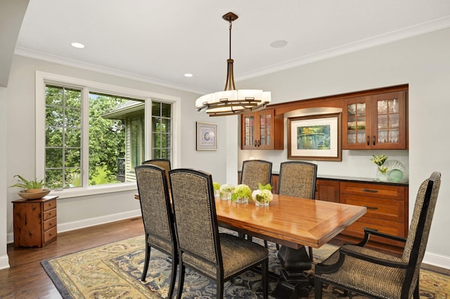 dining space featuring dark wood-type flooring, a wealth of natural light, ornamental molding, and a chandelier