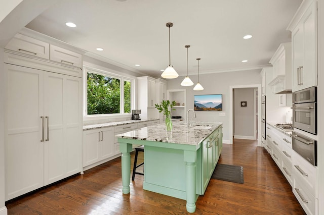 kitchen with decorative light fixtures, light stone countertops, a kitchen island, white cabinets, and sink