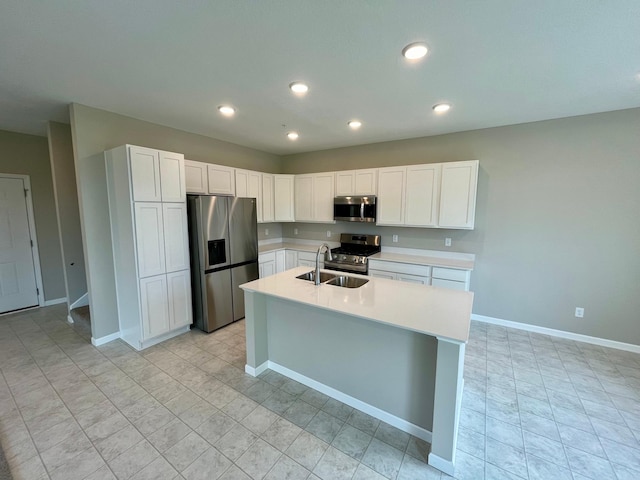 kitchen with an island with sink, sink, stainless steel appliances, and white cabinetry