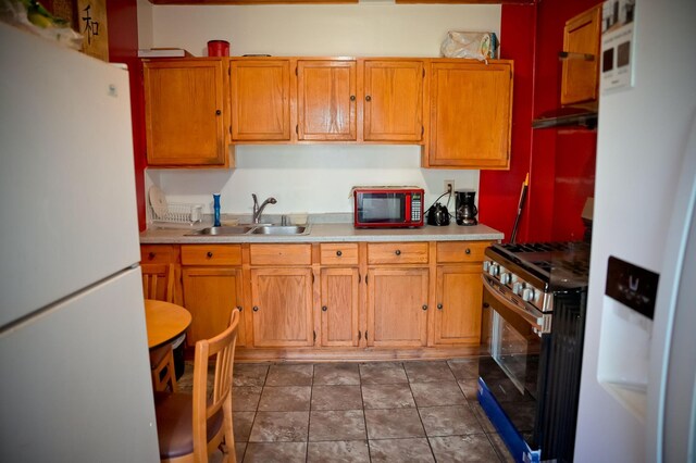 kitchen featuring stainless steel gas stove, sink, white refrigerator with ice dispenser, and white refrigerator