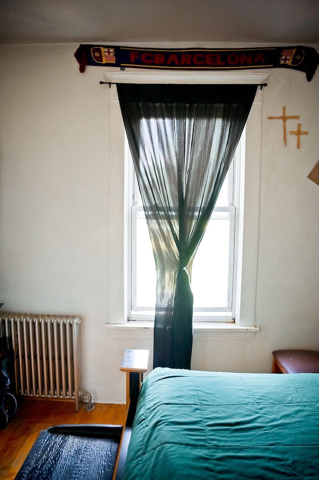 bedroom featuring hardwood / wood-style floors and radiator heating unit