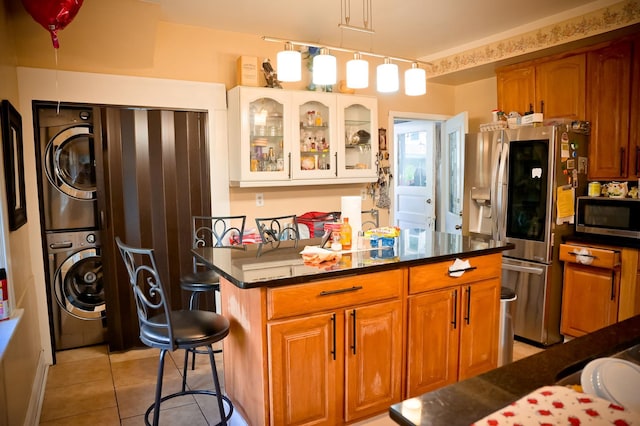 kitchen featuring white cabinetry, stacked washer / drying machine, a breakfast bar area, stainless steel appliances, and pendant lighting