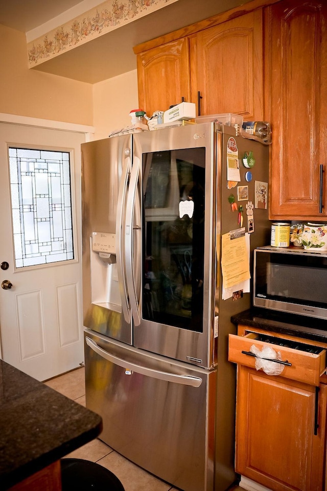 kitchen with light tile patterned floors and stainless steel refrigerator