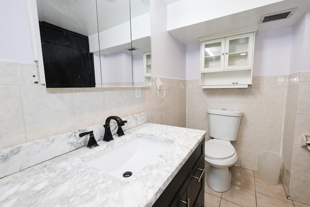 bathroom featuring tile walls, toilet, vanity, and tile patterned flooring