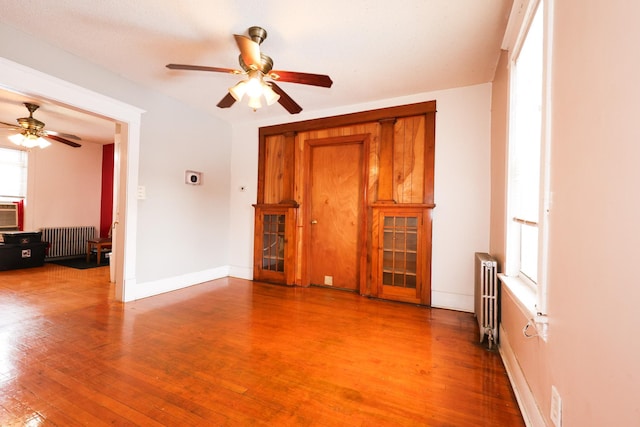 unfurnished room featuring ceiling fan, radiator, and hardwood / wood-style flooring