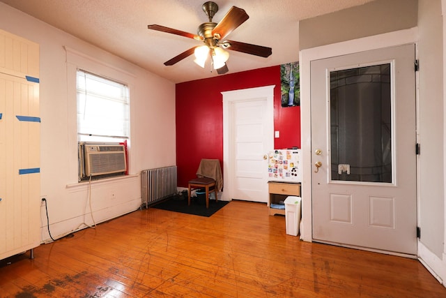 entryway featuring a textured ceiling, radiator heating unit, cooling unit, light hardwood / wood-style floors, and ceiling fan