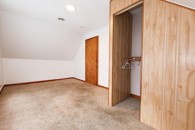 additional living space with light colored carpet and vaulted ceiling