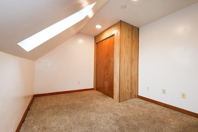 additional living space featuring carpet and lofted ceiling with skylight