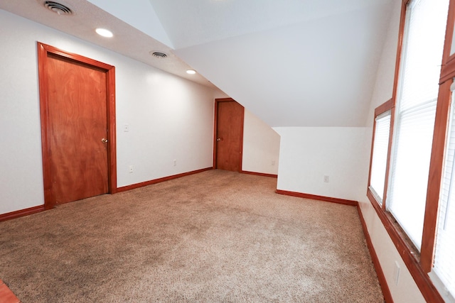 additional living space featuring lofted ceiling and light colored carpet