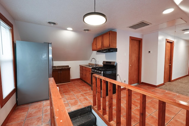 kitchen featuring a textured ceiling, lofted ceiling, stainless steel appliances, sink, and light tile patterned floors