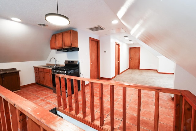 kitchen featuring lofted ceiling, stainless steel gas range oven, sink, a textured ceiling, and light tile patterned floors