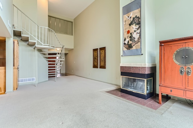 unfurnished living room featuring carpet, a fireplace, and a towering ceiling