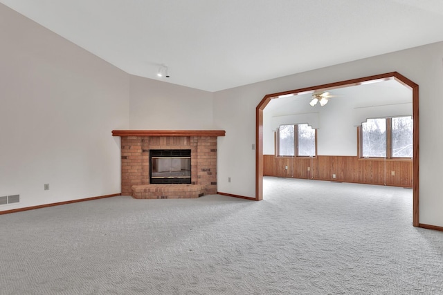 unfurnished living room featuring ceiling fan, carpet flooring, lofted ceiling, and a fireplace