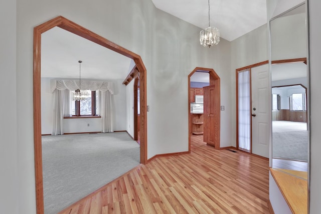 foyer entrance with light colored carpet and an inviting chandelier