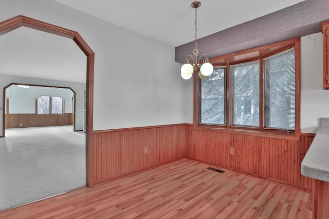 unfurnished dining area featuring a notable chandelier and light hardwood / wood-style floors