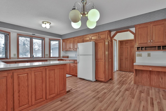 kitchen with a notable chandelier, light hardwood / wood-style floors, sink, a textured ceiling, and white refrigerator