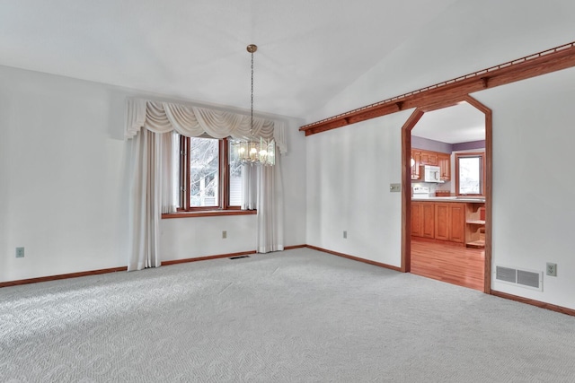 spare room with vaulted ceiling, light colored carpet, and a notable chandelier