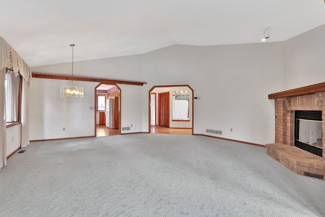 unfurnished living room with a brick fireplace, light colored carpet, a chandelier, and vaulted ceiling