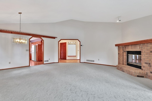 unfurnished living room featuring vaulted ceiling, a chandelier, a fireplace, and carpet floors