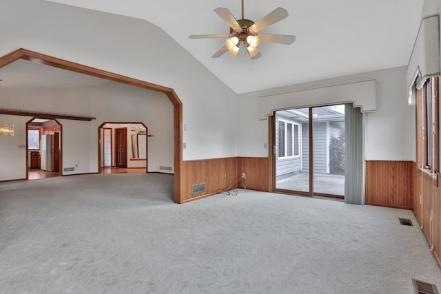 spare room with ceiling fan with notable chandelier, plenty of natural light, light carpet, and lofted ceiling