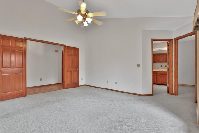 unfurnished bedroom featuring ceiling fan, light colored carpet, vaulted ceiling, and connected bathroom