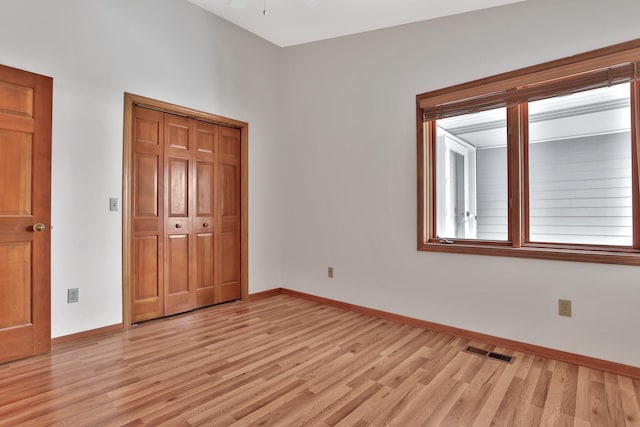 unfurnished bedroom with a closet, lofted ceiling, and light hardwood / wood-style floors