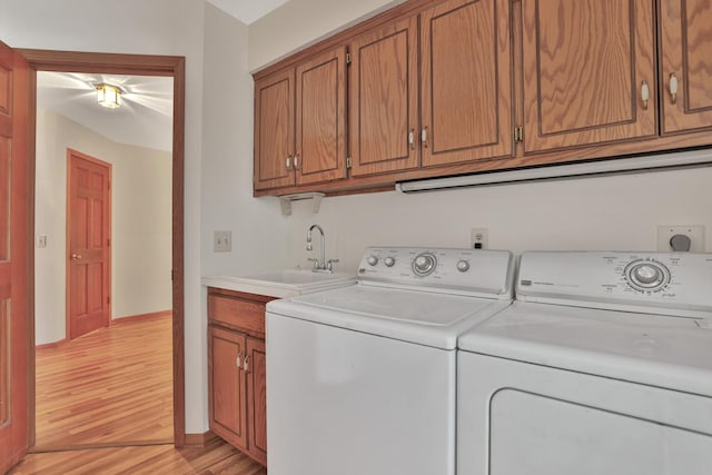 washroom featuring light hardwood / wood-style flooring, sink, washing machine and clothes dryer, and cabinets