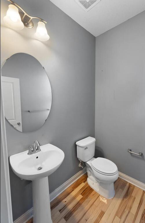 bathroom featuring wood-type flooring and toilet