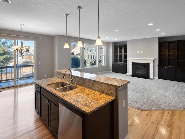 kitchen featuring pendant lighting, dishwasher, sink, and a center island with sink