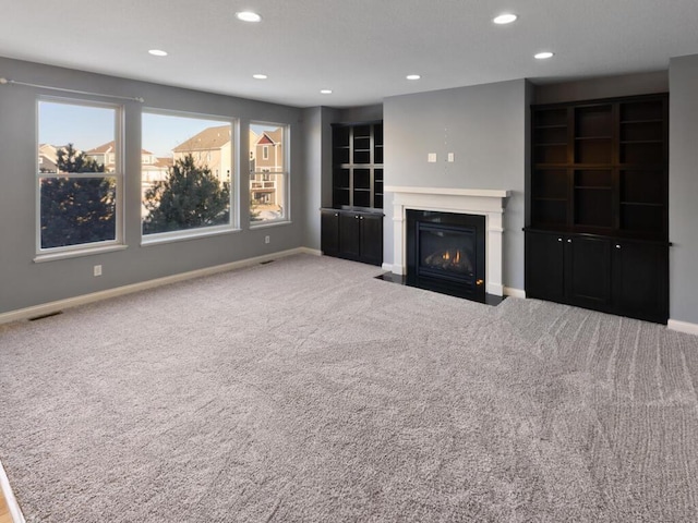 unfurnished living room featuring carpet flooring and a wealth of natural light