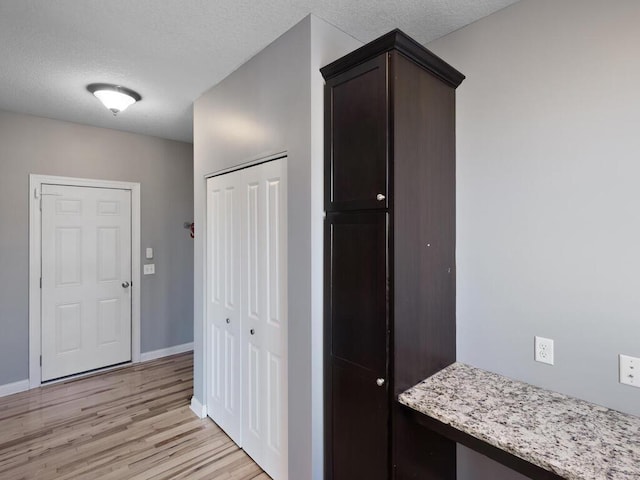 hallway with a textured ceiling and light wood-type flooring