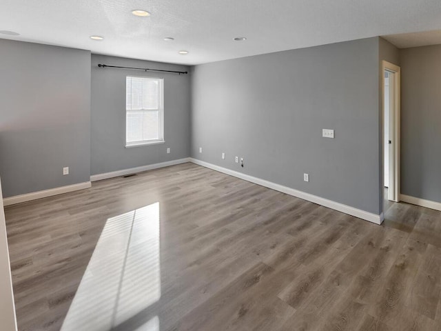 unfurnished room with hardwood / wood-style floors and a textured ceiling