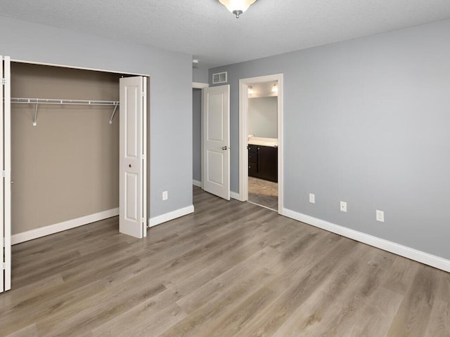 unfurnished bedroom featuring hardwood / wood-style floors, a closet, and a textured ceiling