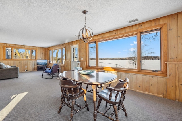 dining room with carpet flooring, a textured ceiling, and a notable chandelier