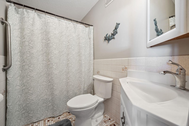 bathroom featuring vanity, tile walls, a textured ceiling, and toilet