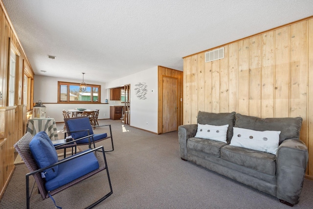 7364 Isaak Ave NW, Annandale, MN 55302 - living area featuring wood walls, carpet floors, a textured ceiling, a chandelier, and baseboards